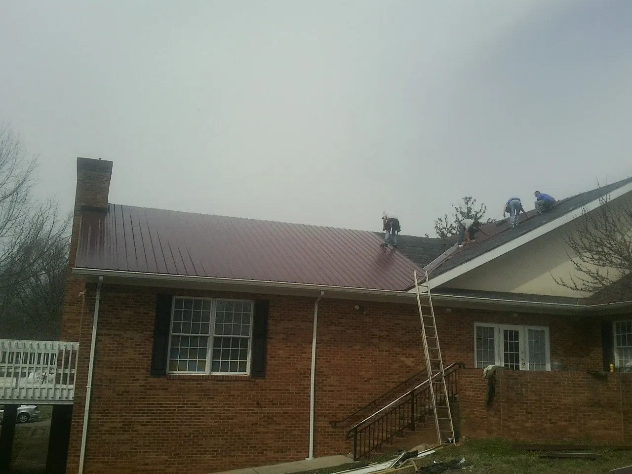 Crew setting red metal roofing panels on a brick home in Ocean View