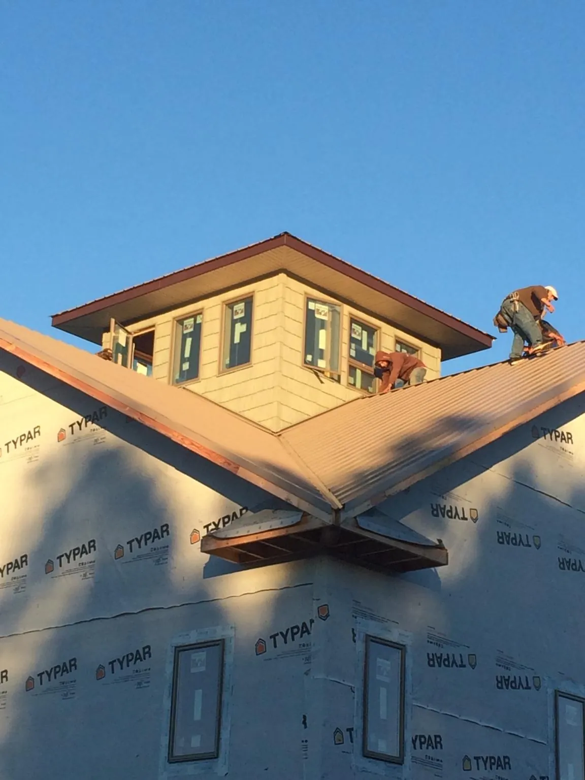 Roofers working around a rooftop cupola on a new metal roof at sunset — Roof Waterproofing in Ocean View by Roofing Brothers